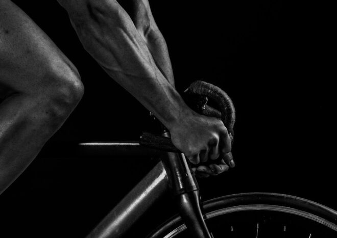 Närbild av cyklistens händer på bockstyret under intensiv cykling